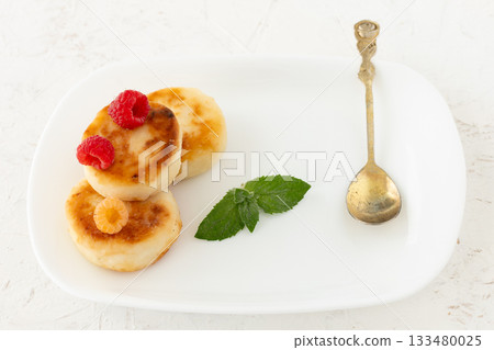 Curd fritters with raspberries on the white plate. 133480025