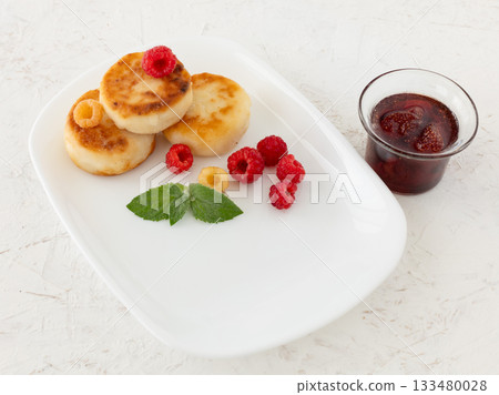 Curd fritters with raspberries and strawberry jam. 133480028