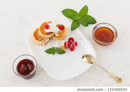 Curd fritters with sour cream, raspberries, strawberry jam and honey. Curd fritters with sour cream, raspberries, strawberry jam and honey. 133480034
