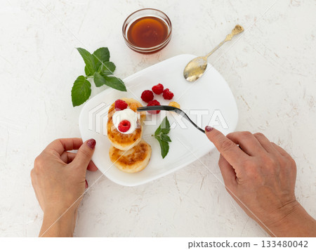 Curd fritters with sour cream, raspberries and honey. 133480042