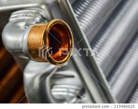 Close-up view of a metallic automotive part showcasing intricate details and vibrant copper finish in a workshop setting Close-up view of a metallic automotive part showcasing intricate details and vibrant copper finish in a workshop setting 133480820