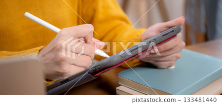 Closeup hand young asian woman working on tablet while managing and planning online business. Closeup hand young asian woman working on tablet while managing and planning online business. 133481440
