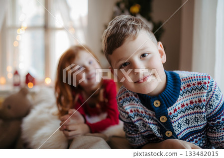 Small girl and boy in pajamas indoors at home at Christmas, playing. 133482015