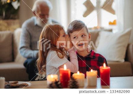 Small girl and boy sharing secret. Christmas at home. Small girl and boy sharing secret. Christmas at home. 133482090