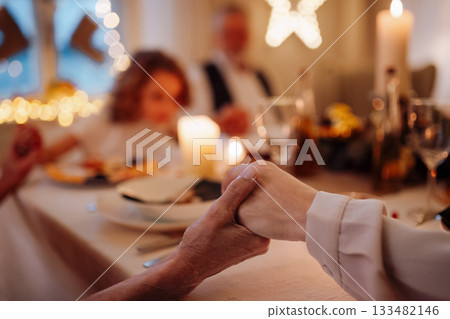 Family holding hands in prayer during Christmas dinner. Family holding hands in prayer during Christmas dinner. 133482146