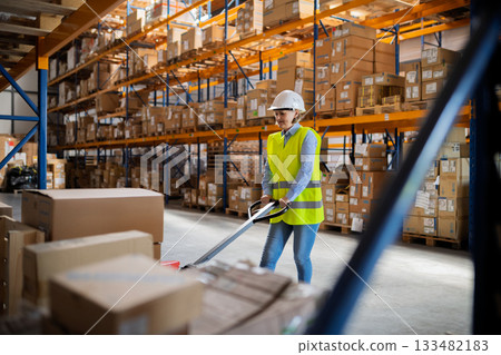Older woman as warehouse worker pulling a pallet truck with boxes. Older woman as warehouse worker pulling a pallet truck with boxes. 133482183