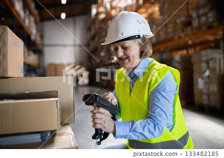 Senior warehouse woman worker working with barcode scanner. 133482185