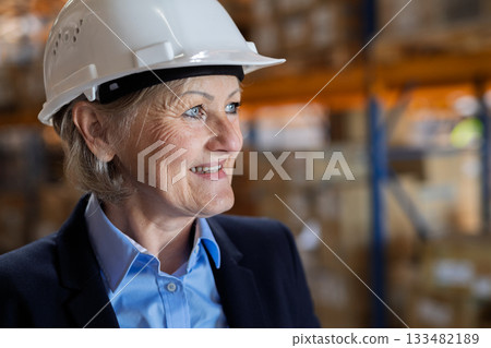 Older female warehouse manager or supervisor with helmet. Older female warehouse manager or supervisor with helmet. 133482189