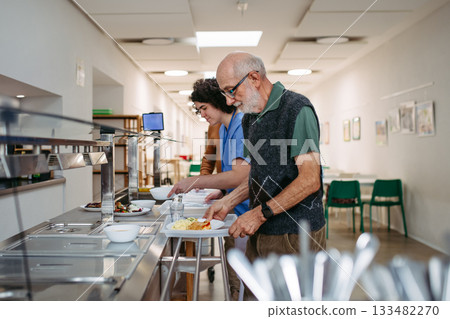 Group of seniors having lunch in community center cafeteria. 133482270