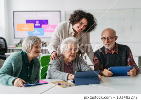 Group of seniors learning digital skills with tutor support in community center. 133482272