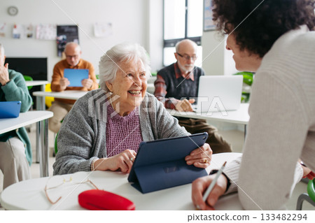 Elderly woman learning digital skills with tutor help. 133482294