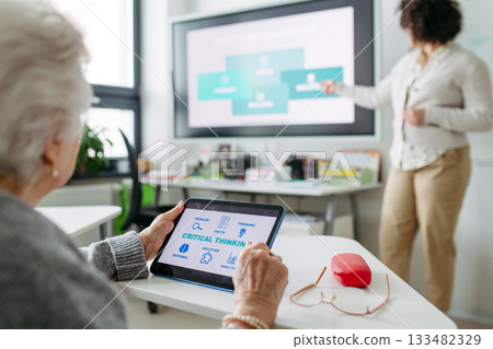 Elderly woman learning digital skills with tutor help. 133482329