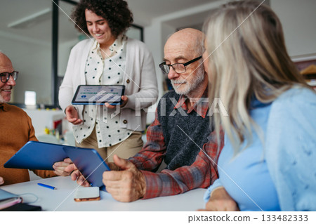 Group of senior people learning digital skills with tutor help. 133482333