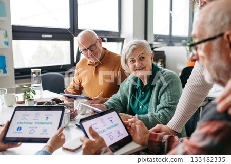 Group of senior people learning digital skills with tutor help. 133482335