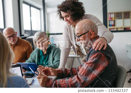 Group of senior people learning digital skills with tutor help. 133482337