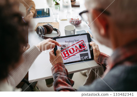 Volunteer teaching seniors how to recognize fake news on digital tablet. Volunteer teaching seniors how to recognize fake news on digital tablet. 133482341