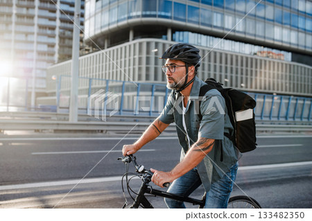 Male cyclist riding bike down the street. 133482350