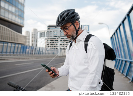 Manager on bike, reading text message on phone. 133482355