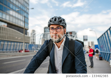 City commuter riding bike to office, wearing backpack and helmet. 133482365