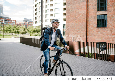 City commuter riding bike to office, wearing backpack and helmet. City commuter riding bike to office, wearing backpack and helmet. 133482371