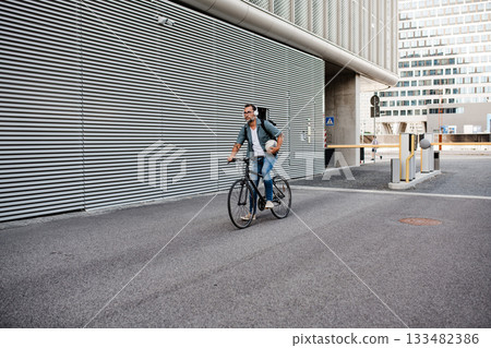 City commuter riding bike on street, wearing backpack. 133482386