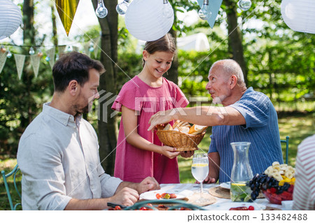 Family sharing food during garden grill party. 133482488