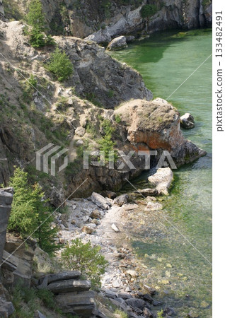 The photograph shows a rocky cliff on Olkhon Island, covered with coniferous trees. 133482491