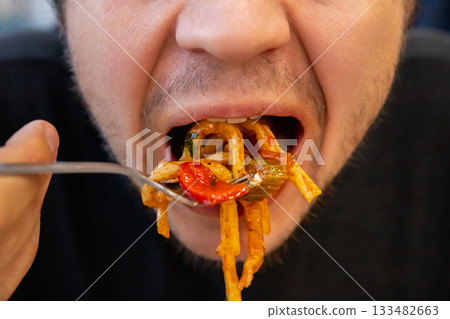 chewing mouth close up view. man eating Lagman noodles, hand holds a fork. Gluttony, overeating, diabetes, diet failure. chewing mouth close up view. man eating Lagman noodles, hand holds a fork. Gluttony, overeating, diabetes, diet failure. 133482663