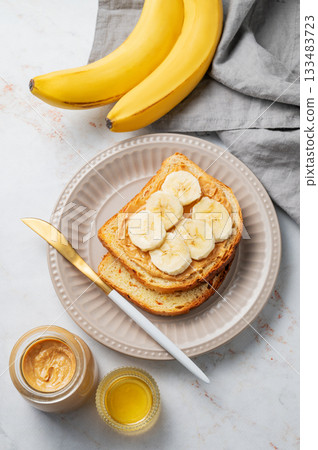 Peanut butter sandwich and banana on a plate on a marble background Peanut butter sandwich and banana on a plate on a marble background 133483723