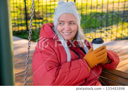 A happy, body-positive Caucasian woman with a paper coffee mug in an autumn park. Portrait of a smiling 47 year old woman. Mental health, natural beauty, positive emotions A happy, body-positive Caucasian woman with a paper coffee mug in an autumn park. Portrait of a smiling 47 year old woman. Mental health, natural beauty, positive emotions 133483896