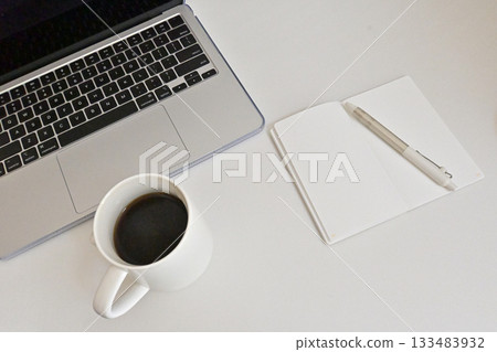 A simple morning start: coffee, a desk with a laptop and a notebook A simple morning start: coffee, a desk with a laptop and a notebook 133483932