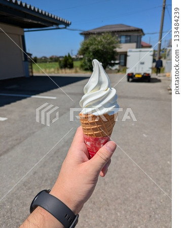 Holding a soft serve ice cream under the blue sky Holding a soft serve ice cream under the blue sky 133484239