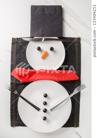 beautiful Christmas or New Year's table setting featuring a snowman. Viewed from above beautiful Christmas or New Year's table setting featuring a snowman. Viewed from above 133484251