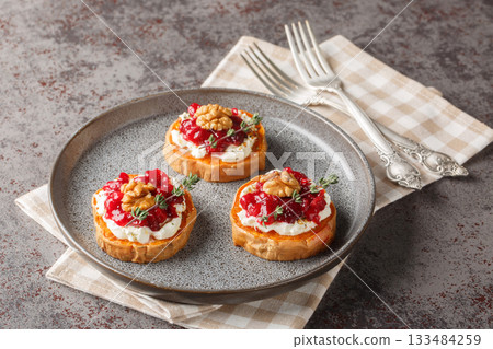 portioned sweet potato appetizer with cream cheese, cranberry sauce, thyme, spices and walnuts close-up in a plate. Horizontal portioned sweet potato appetizer with cream cheese, cranberry sauce, thyme, spices and walnuts close-up in a plate. Horizontal 133484259