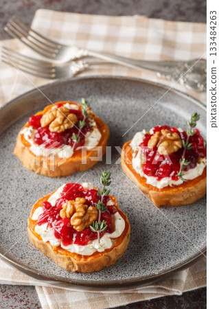 baked sweet potato appetizer with cream cheese, cranberry jam, spices and walnuts close-up in a plate. Vertical baked sweet potato appetizer with cream cheese, cranberry jam, spices and walnuts close-up in a plate. Vertical 133484263