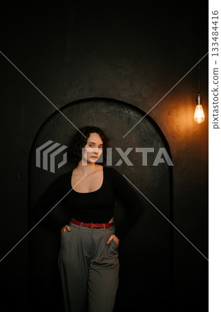 Thoughtful Woman Posing in Stylish Outfit with Lighting Thoughtful Woman Posing in Stylish Outfit with Lighting 133484416