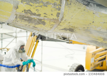 Aircraft maintenance technician working on fuselage repair in an aviation hangar during the daytime to ensure safety and performance of the aircraft structure Aircraft maintenance technician working on fuselage repair in an aviation hangar during the daytime to ensure safety and performance of the aircraft structure 133484808