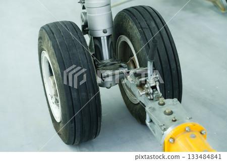 Detailed view of a dual tire aircraft landing gear at an aviation maintenance facility during daylight hours showcasing the mechanical components Detailed view of a dual tire aircraft landing gear at an aviation maintenance facility during daylight hours showcasing the mechanical components 133484841