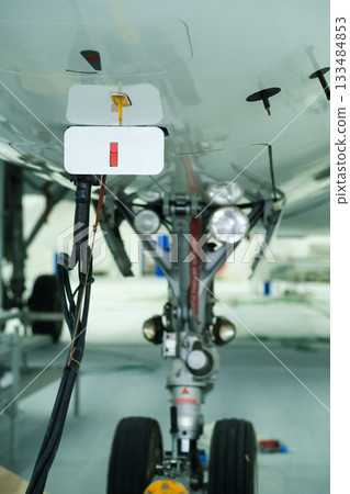 Close-up view of aircraft landing gear and components at an aircraft maintenance facility during daytime inspection 133484853