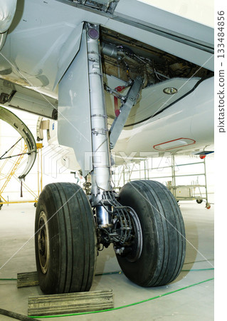 Landing gear maintenance and inspection of an aircraft located in a hangar with tools and equipment visible nearby during daylight hours Landing gear maintenance and inspection of an aircraft located in a hangar with tools and equipment visible nearby during daylight hours 133484856