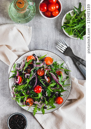 A delicious salad of beans, tomatoes, herbs and onions on a plate top and vertical view 133485189