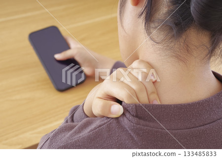 一位頸部和肩部疼痛的女子正在操作智慧型手機 133485833