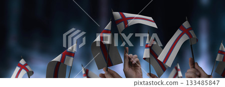 Faroe Islands flags in their hands on a blurred urban background Faroe Islands flags in their hands on a blurred urban background 133485847