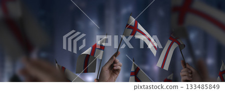 Faroe Islands flags in their hands on a blurred urban background Faroe Islands flags in their hands on a blurred urban background 133485849