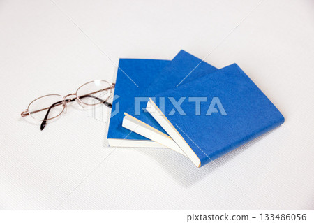 Glasses and three books with blue book covers 133486056