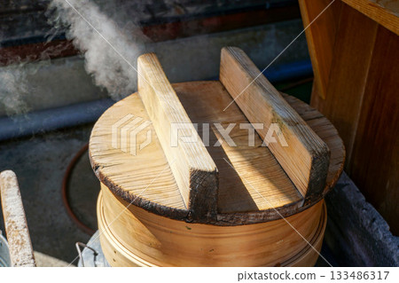 A round wooden steamer with white steam rising from it A round wooden steamer with white steam rising from it 133486317