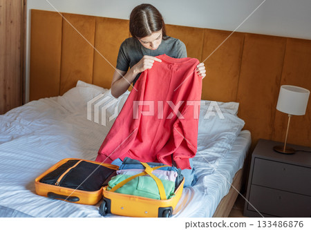Woman packing clothes for travel trip preparing suitcase Woman packing clothes for travel trip preparing suitcase 133486876