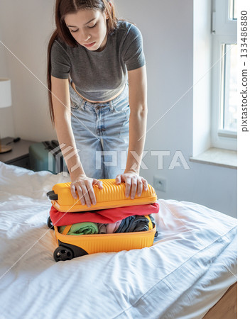 Woman packing overstuffed suitcase for upcoming trip 133486880