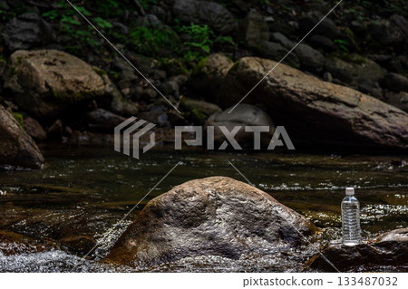 A plastic bottle placed on a rock in a clear stream, natural water and a refreshing feeling A plastic bottle placed on a rock in a clear stream, natural water and a refreshing feeling 133487032