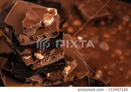 Stacked broken chocolate pieces with nuts in warm soft focus creating a rich artisan dessert scene ideal for confectionery branding and advertising visuals Stacked broken chocolate pieces with nuts in warm soft focus creating a rich artisan dessert scene ideal for confectionery branding and advertising visuals 133487186